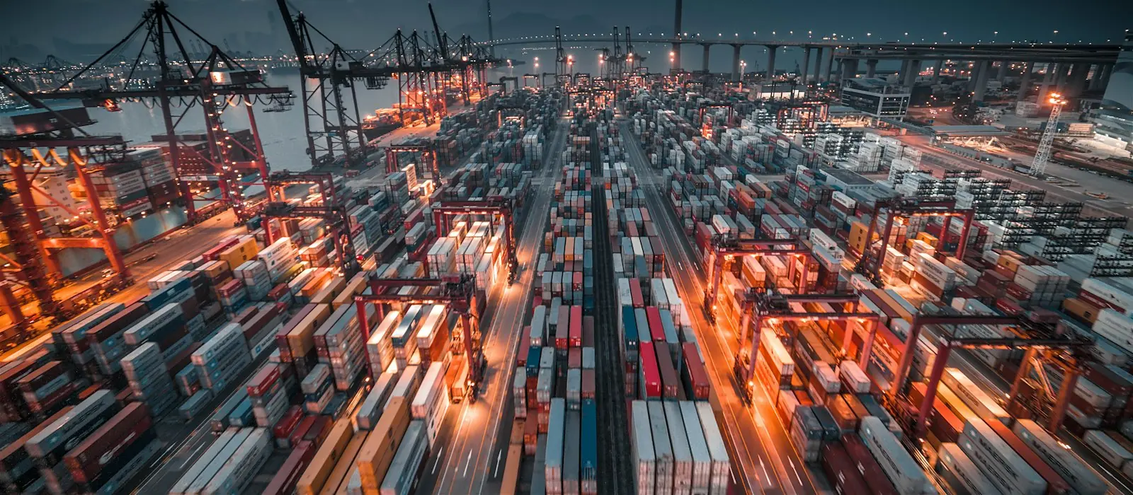 Stacked shipping containers and cranes at a container port
